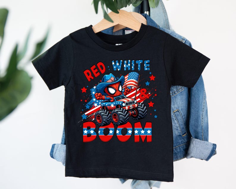 A black t-shirt with a graphic design featuring a Spider-Man character, a Jeep, and the text "RED WHITE BOOM" against a patriotic background.