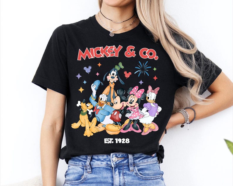 A woman wearing a black t-shirt with a graphic of Disney characters and the text "MICKEY & CO." printed on it.