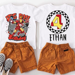 A white t-shirt with a graphic design and the number 4, along with a pair of brown shorts and black and white checkered sneakers.