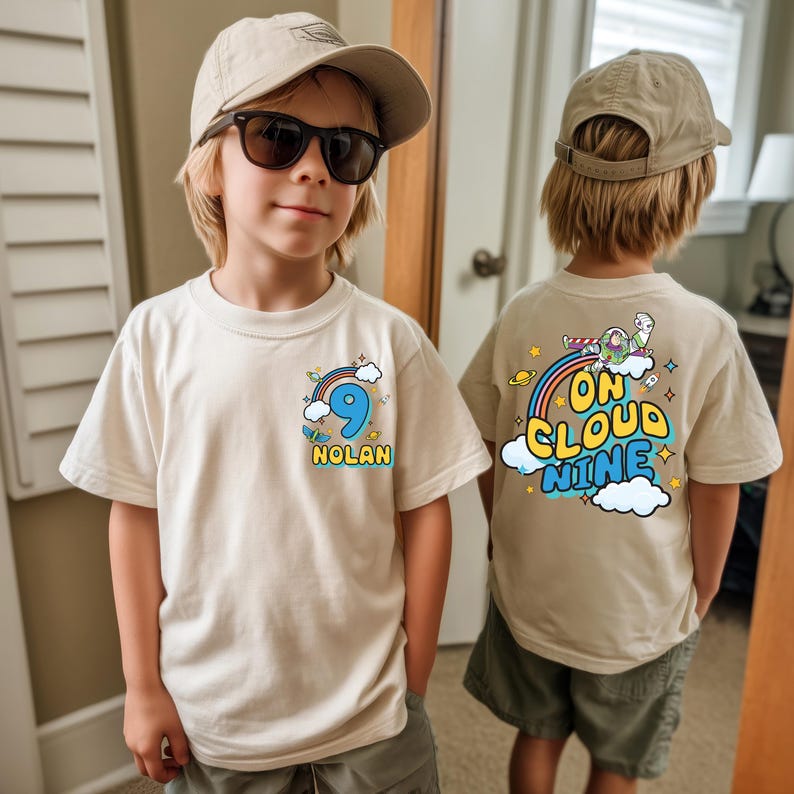 A young boy wearing a white t-shirt with a number 9 and a cloud graphic, standing in a room with a door and a window in the background.