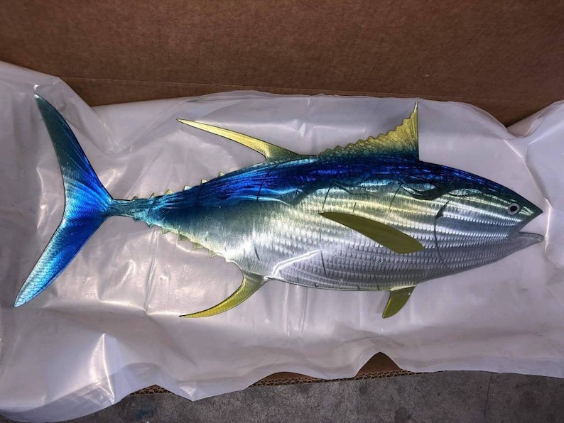May include: A metal sculpture of a tuna fish with blue, green, and yellow paint. The fish is depicted in a realistic style with detailed scales and fins.