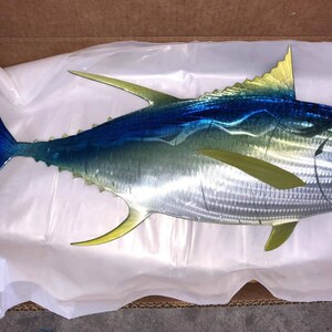 May include: A metal sculpture of a blue and yellow fish. The fish is made of metal and has a realistic design. The fish is a popular home decor item.