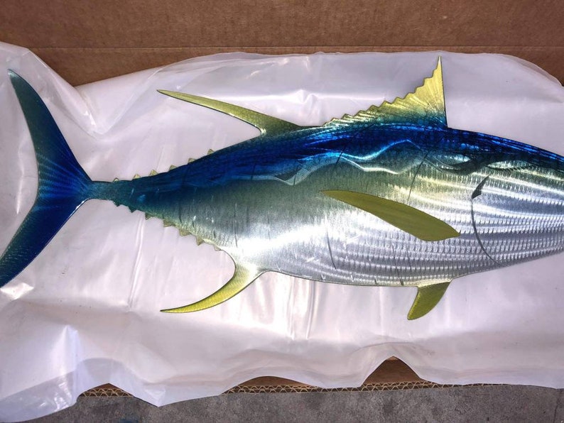 May include: A metal sculpture of a blue and yellow fish. The fish is made of metal and has a realistic design. The fish is a popular home decor item.