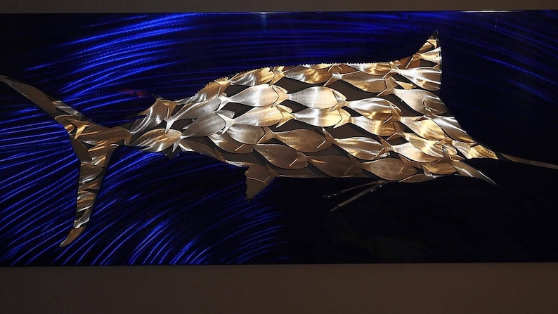Puede incluir: Una escultura de marlin de metal dorado sobre un fondo azul. El marlin est&aacute; hecho de muchas peque&ntilde;as formas de peces.