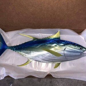May include: A metal sculpture of a yellowfin tuna with blue and yellow accents. The sculpture is made of metal and has a realistic appearance.