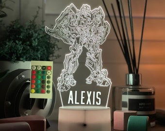 May include: A white 3D printed night light shaped like a robot with the name "Alexis" printed below. The light is on a white base and has a remote control with multiple color options.