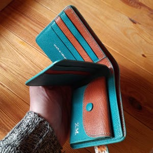May include: Open teal and brown leather wallet with multiple card slots and a coin pouch. The wallet has a snap closure and the text "Made in Ukraine" is visible. The wallet is open, revealing the interior design.
