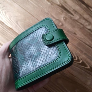 May include: A green leather wallet with a snakeskin pattern and a snap closure.