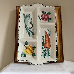 May include: A white ceramic serving dish with four compartments. Each compartment features a hand-painted design of vegetables, including a carrot, a courgette, a pepper, and a tomato.
