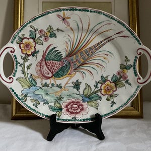 May include: Oval serving platter with a hand-painted pheasant design. The white ceramic platter features a colorful pheasant, flowers, and foliage. It has two handles and measures approximately 14 inches in length.