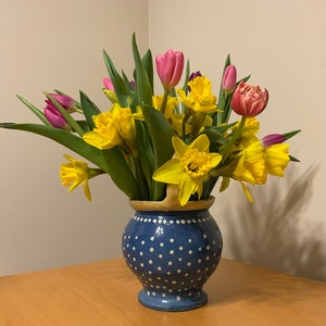 Può includere: Un vaso di ceramica blu e bianco a pois pieno di un mazzo di narcisi gialli e tulipani rosa.