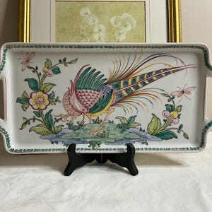 May include: Rectangular ceramic serving tray with a hand-painted pheasant design. The tray features a white background with a green border and handles. The pheasant is depicted in vibrant colors, surrounded by floral and botanical elements.
