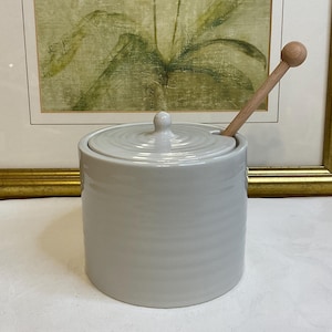 Vasetto o barattolo per miele in ceramica grigio chiaro con dosatore in legno, decorazione a coste, in perfette condizioni.
