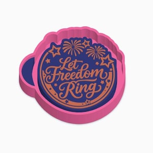 Könnte beinhalten: Rosa-blauer Ausstecher mit dem Schriftzug "Let Freedom Ring". Das Design umfasst Feuerwerk und Sterne, ideal zum Backen für patriotische Anlässe.