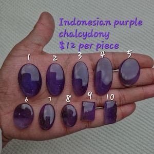 May include: Ten polished purple chalcedony stones, numbered 1 through 10, are displayed on a hand. The stones are oval shaped, except for stones 9 and 10, which are rectangular. The text "Indonesian purple chalcedony $12 per piece" is visible above the stones.