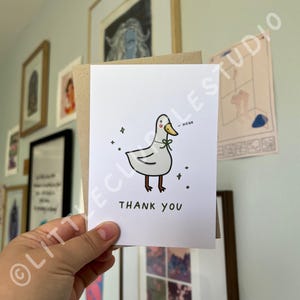 May include: A white card with a cartoon illustration of a duck wearing a green bow tie. The duck is saying "Honk" in a speech bubble. The card says "Thank You" in black text.