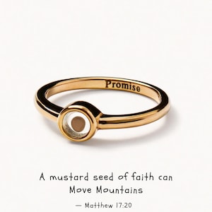 Puede incluir: Un anillo de tono dorado con un engaste circular que contiene una pequeña semilla de mostaza. La banda interior del anillo está grabada con la palabra Promise. Debajo del anillo, el texto dice: A mustard seed of faith can Move Mountains — Matthew 17:20.
