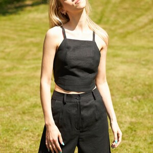Puede incluir: Una mujer con un top corto de lino negro y pantalones cortos a juego. El atuendo es simple y elegante, perfecto para un d&iacute;a de verano.