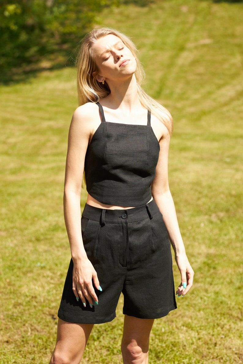 Puede incluir: Una mujer con un top corto de lino negro y pantalones cortos a juego. El atuendo es simple y elegante, perfecto para un d&iacute;a de verano.