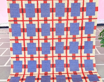 May include: A blue and red geometric patterned rug with a fringe border. The rug has a checkered pattern with squares of blue and red.