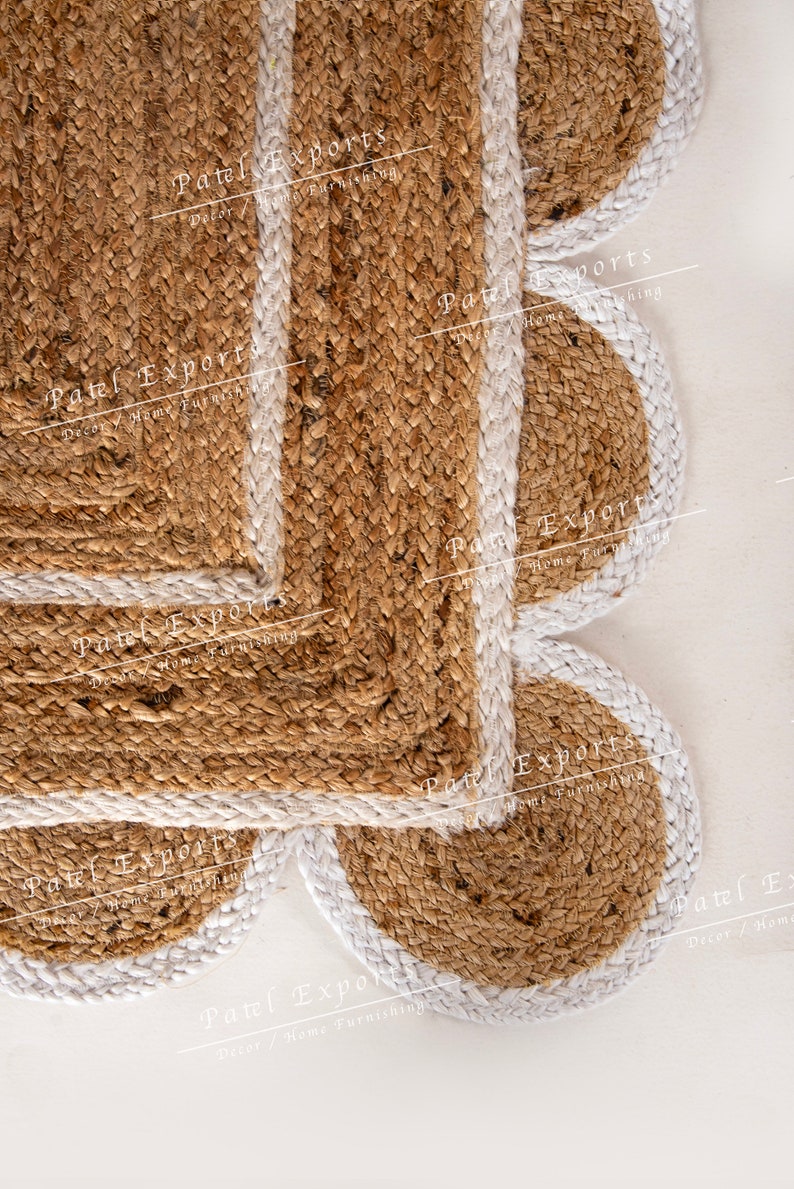 Op de afbeelding: Een bruin jute vloerkleed met een witte rand. Het vloerkleed is gemaakt van verschillende overlappende cirkels. Het vloerkleed heeft de tekst "Patel Exports Decor/Home Furnishing" erop gedrukt.