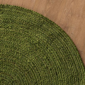 Könnte beinhalten: Ein runder, grüner Jute-Teppich mit gewebter Struktur. Der Teppich ist aus Naturfasern gefertigt und hat einen rustikalen, erdigen Look.