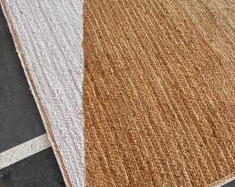 Puede incluir: Una alfombra rectangular de yute con un diseño geométrico blanco y marrón. La alfombra tiene un borde blanco y está hecha de fibras naturales.