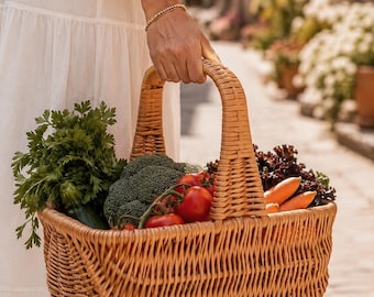 May include: A light brown woven wicker basket with a high arched handle, filled with fresh produce including green parsley, a head of broccoli, red tomatoes on the vine, orange carrots, and dark purple leafy greens, held by a person in a white dress.