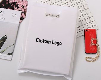 Op de afbeelding: Witte plastic tas met een uitgestanste handvat en de tekst "Custom Logo" in zwart gedrukt.