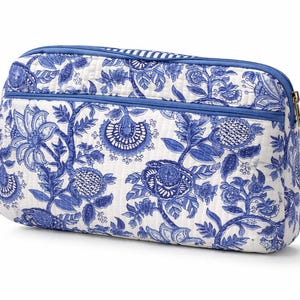 May include: A rectangular, quilted cosmetic bag with a blue and white floral pattern. The bag has a blue zipper and trim, and a gold-colored zipper pull. The floral design features stylized flowers and foliage.