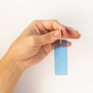 Puede incluir: Una mano sosteniendo una etiqueta de llave azul claro con un anillo dorado.