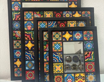 Op de afbeelding: Set van vier zwart geframed spiegels met kleurrijke tegelontwerpen. De tegels zijn in verschillende tinten blauw, geel, rood en groen. De spiegels zijn in elkaar genest, met de grootste spiegel aan de achterkant en de kleinste spiegel aan de voorkant.