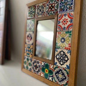May include: A wooden framed mirror with a mosaic of colourful tiles in a geometric pattern. The tiles are in shades of blue, green, yellow, red, and white.