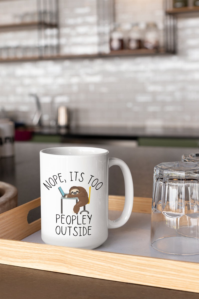 May include: White ceramic mug with a black and brown sloth illustration. The mug has the text "NOPE, ITS TOO PEOPLEY OUTSIDE" printed on it.