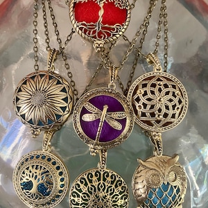Peut inclure: Plusieurs colliers pendentifs de couleur or antique avec divers motifs, dont un arbre, un tournesol, une libellule et un hibou. Chaque pendentif est suspendu à une chaîne délicate. Les pendentifs présentent des détails complexes et des fonds colorés.