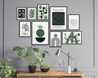 May include: A collection of framed art prints in various sizes and designs, featuring botanical and abstract themes in shades of green and white. Some prints include text. The artwork is displayed on a gray wall.
