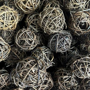 May include: A close-up of a group of brown woven balls made of natural twigs. The balls are arranged in a random pattern, creating a rustic and natural look.