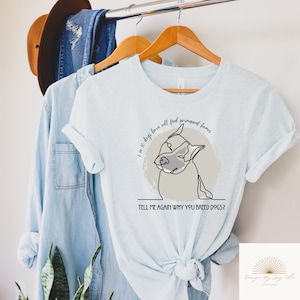May include: Light blue t-shirt with a line drawing of a dog and the text "I in 10 dogs born will find permanent homes. TELL ME AGAIN WHY YOU BREED DOGS?" The shirt is hanging on a wooden hanger.