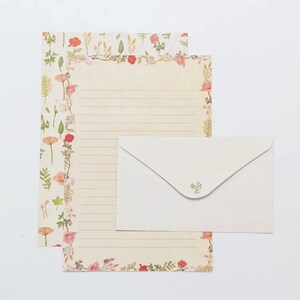 May include: A set of floral stationery with a white envelope. The paper has a floral border with pink and red flowers and green leaves. The envelope has a small floral design in the upper right corner.