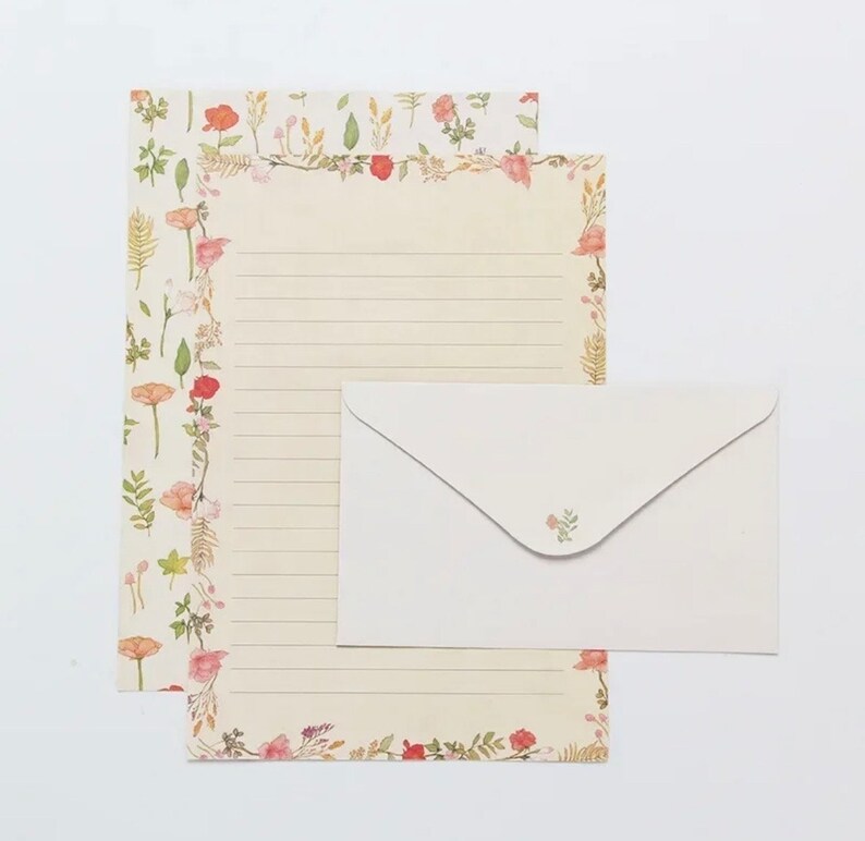 May include: A set of floral stationery with a white envelope. The paper has a floral border with pink and red flowers and green leaves. The envelope has a small floral design in the upper right corner.