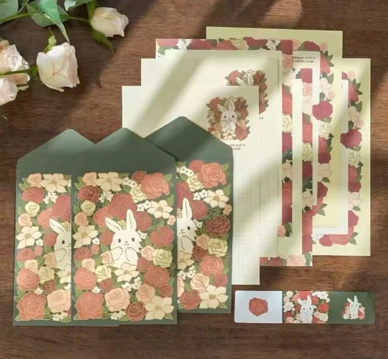 Pu&ograve; includere: Un set di cancelleria con un design floreale con coniglietti. Il set include buste, carta da lettere e un foglio di adesivi. Le buste e la carta da lettere hanno un bordo verde con un motivo floreale e un coniglietto bianco al centro. Il foglio di adesivi ha un motivo floreale con un coniglietto bianco al centro.