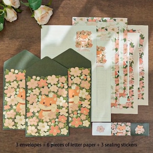 Pu&ograve; includere: Un set di tre buste verdi con un motivo floreale con fiori rosa e un cane Shiba Inu di cartone animato. Il set include anche sei fogli di carta da lettere con un bordo floreale e tre adesivi di sigillatura con un motivo floreale.