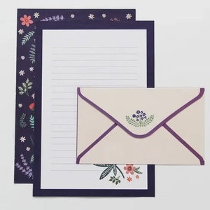 May include: A set of stationery featuring a floral design with a purple, white, and green color scheme. The set includes a letter writing sheet and a matching envelope.