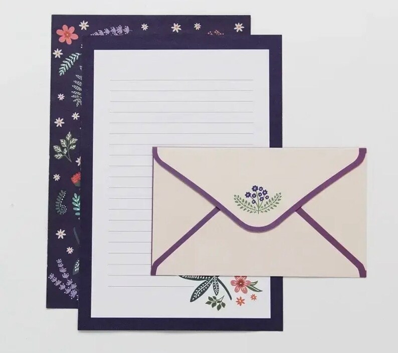 May include: A set of stationery featuring a floral design with a purple, white, and green color scheme. The set includes a letter writing sheet and a matching envelope.