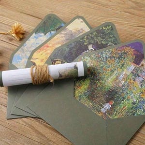 Pu&ograve; includere: Set di cinque buste verdi con una variet&agrave; di dipinti colorati sul davanti. Le buste sono piegate e impilate l'una sull'altra. Un pezzo di carta arrotolato con un dipinto su di esso &egrave; davanti alle buste.