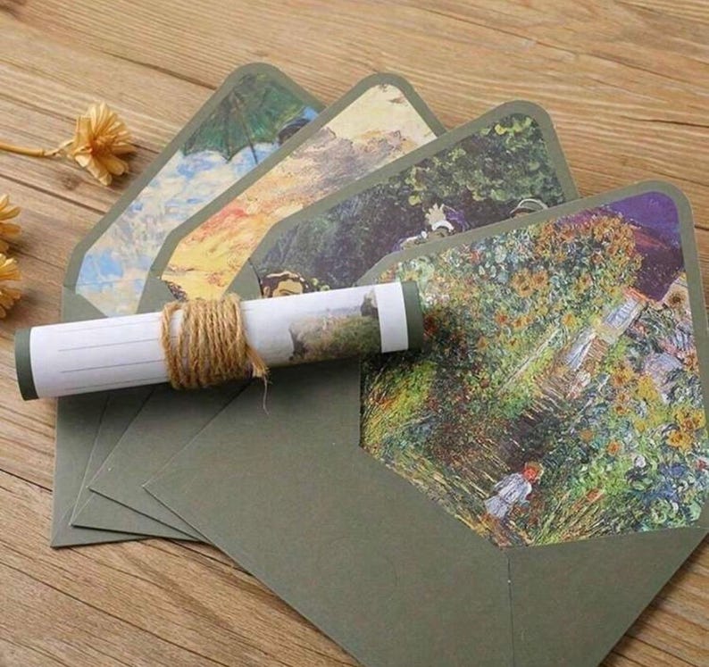 Pu&ograve; includere: Set di cinque buste verdi con una variet&agrave; di dipinti colorati sul davanti. Le buste sono piegate e impilate l'una sull'altra. Un pezzo di carta arrotolato con un dipinto su di esso &egrave; davanti alle buste.
