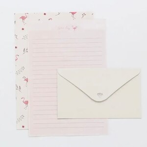 May include: Pink stationery set with a flamingo pattern and a white envelope with a floral design. The stationery has a lined sheet and a decorative sheet with the text "Dear Friend".