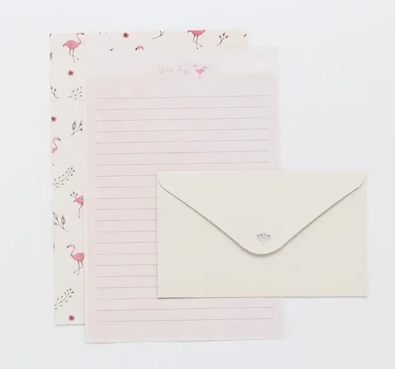 May include: Pink stationery set with a flamingo pattern and a white envelope with a floral design. The stationery has a lined sheet and a decorative sheet with the text "Dear Friend".