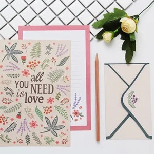 May include: A floral patterned card with the text "You all need is love" and a matching envelope. The envelope has a floral design in the corner.