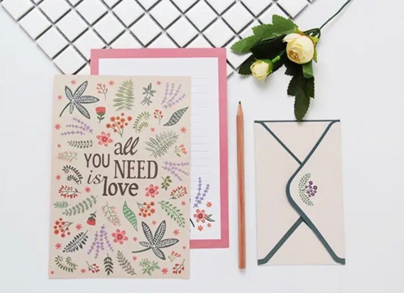 May include: A floral patterned card with the text "You all need is love" and a matching envelope. The envelope has a floral design in the corner.